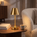 Brass cordless table lamp glowing on a walnut side table, Wick & Wool