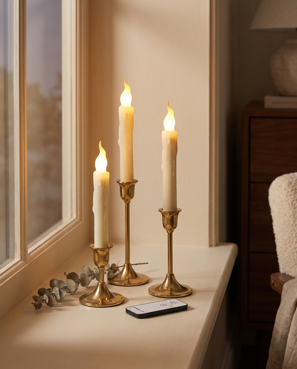 Flameless taper candles on a windowsill with the remote control