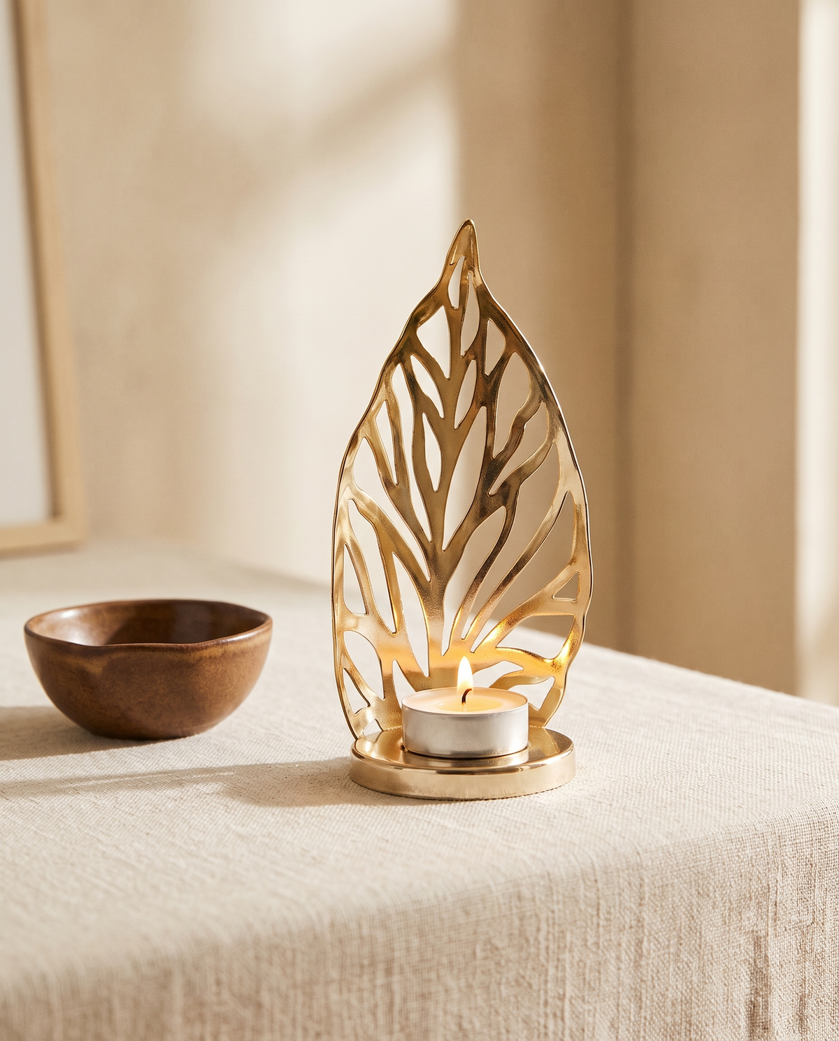 Gold leaf tealight holder on a linen-covered table