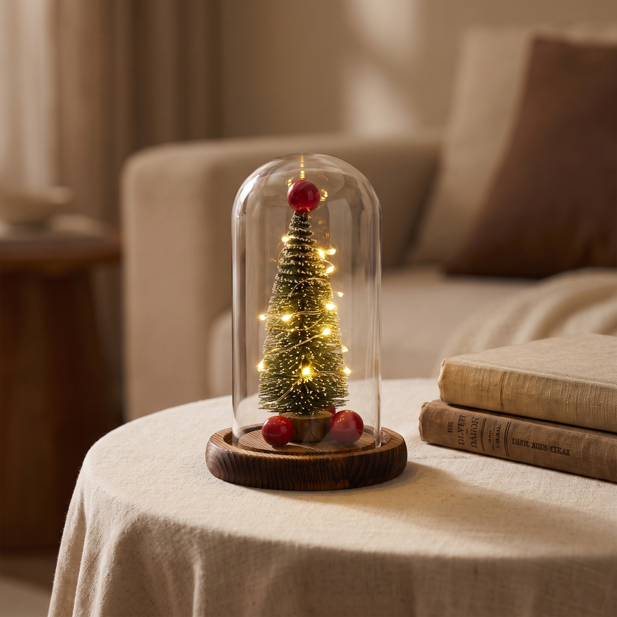 Glass dome Christmas tree lit on a linen-covered side table
